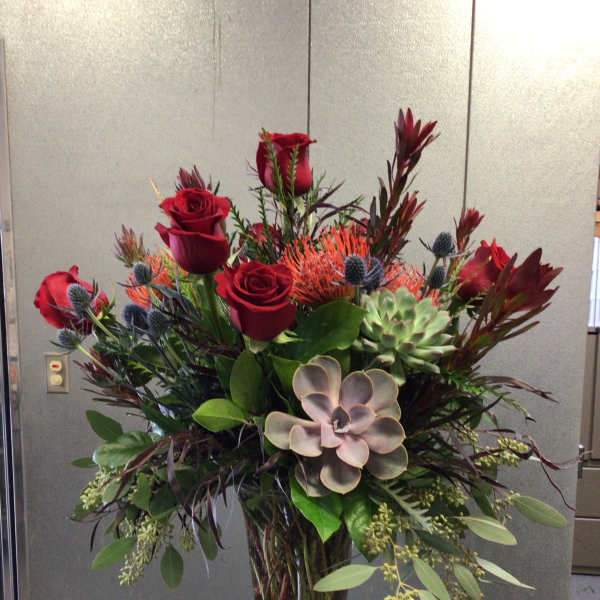 Tall vase arrangement with red roses and succulents