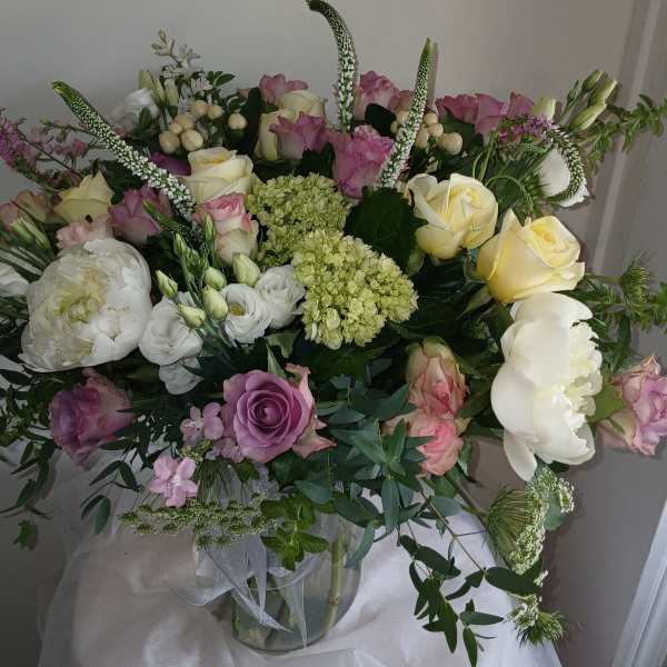 Large bouquet of pink, white, and yellow flowers in a glass vase