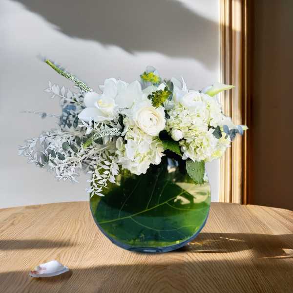 White floral arrangement in a round green glass vase