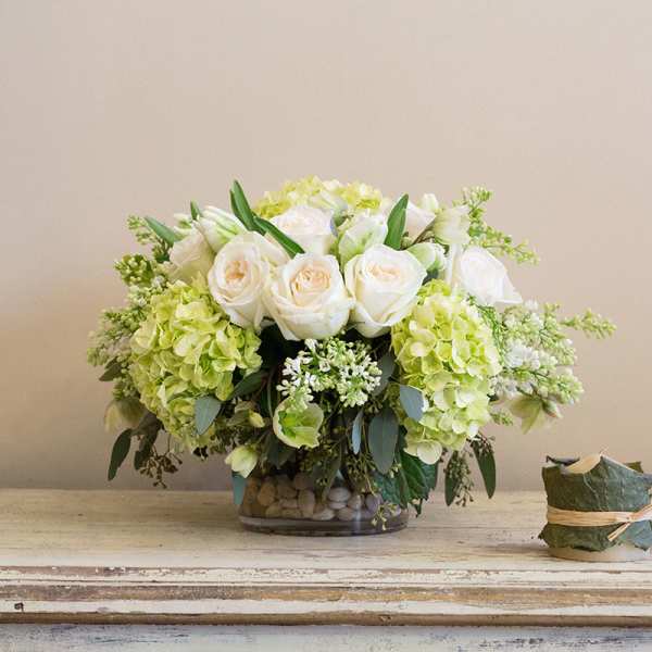 White roses and green hydrangeas in a glass vase