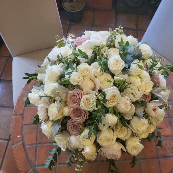 Large bouquet of white and blush roses with greenery on a chair