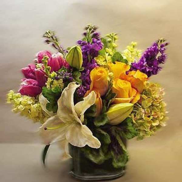 Colorful bouquet of lilies, roses, and purple flowers in a glass vase