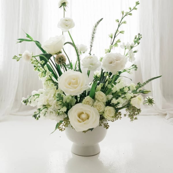 White floral arrangement in a white pedestal vase
