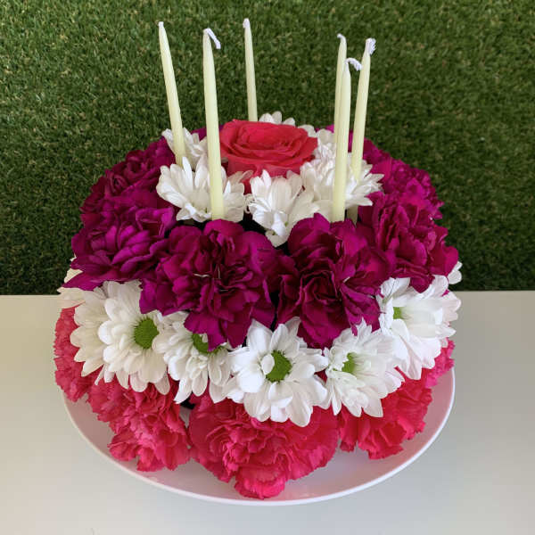 Round floral centerpiece with pink and white flowers and tall candles