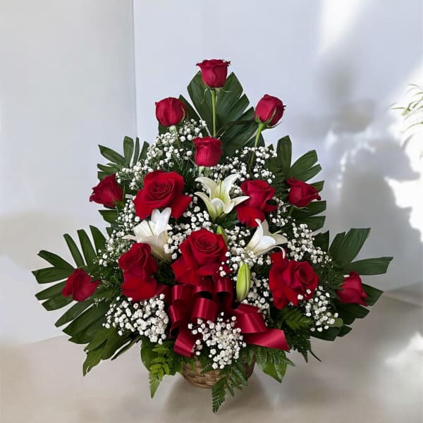 Red roses and white lilies in a basket with baby's breath