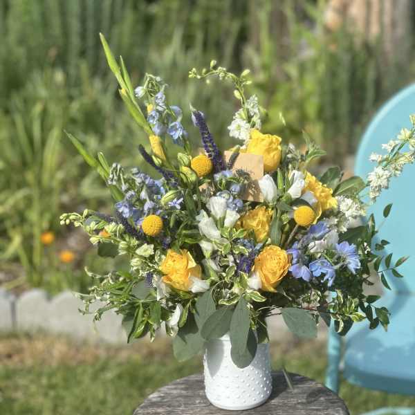 Bouquet of yellow and blue flowers in a white vase