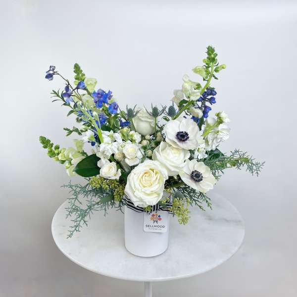 White and blue floral arrangement in a white vase
