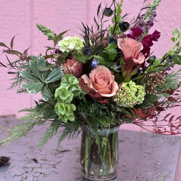 Pink roses and mixed flowers in a clear glass vase