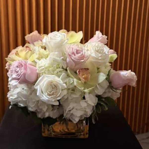 Pastel roses and orchids arranged in a glass vase