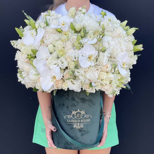 Large white floral arrangement in a dark green hatbox