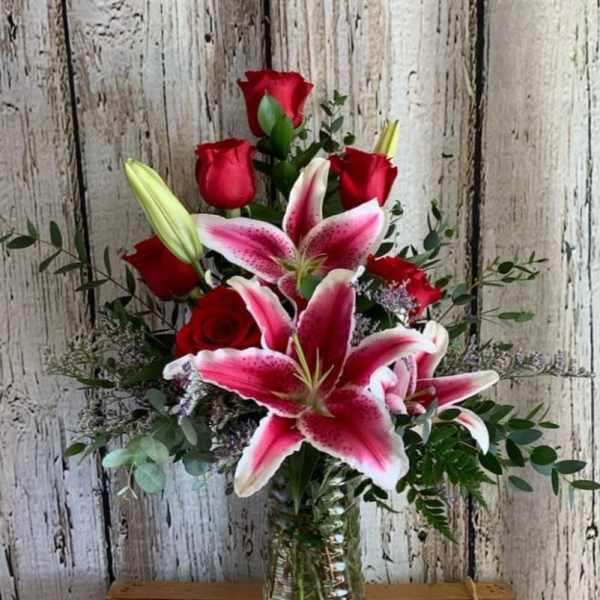Bouquet of red roses and pink lilies in a glass vase