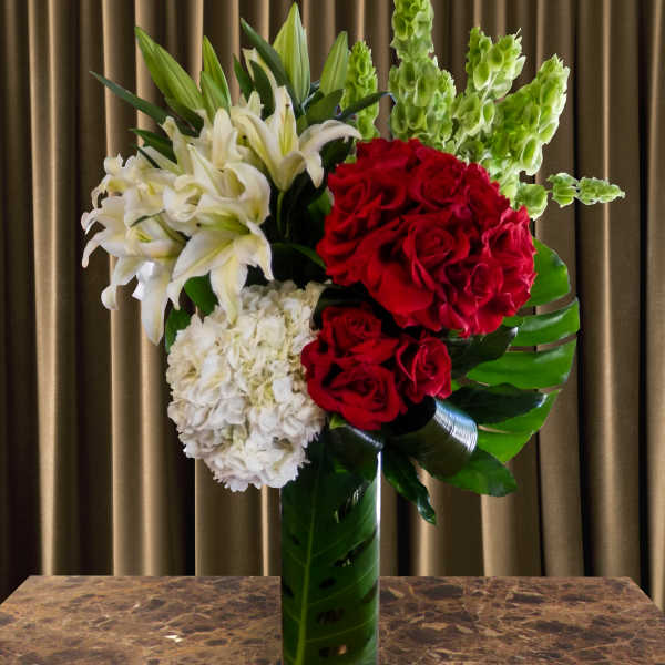 Red roses and white lilies arranged in a tall glass vase