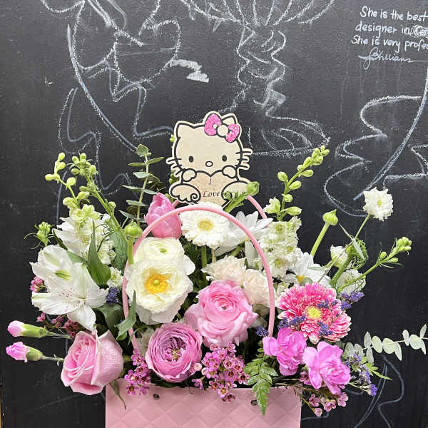 Pink and white flower arrangement in a pink gift bag with a Hello Kitty topper