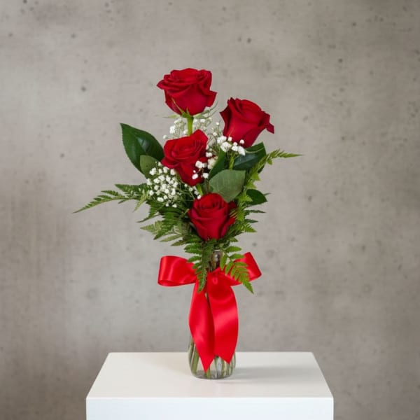 Red roses in a clear glass vase with a red ribbon