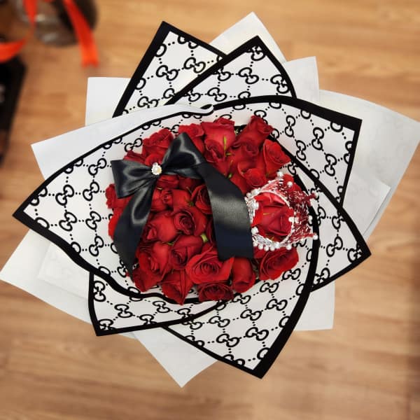 Bouquet of red roses wrapped in black-and-white patterned paper with a black ribbon