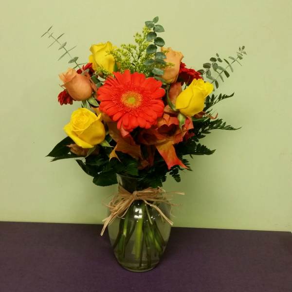 Bouquet of red gerbera daisies and yellow roses in a glass vase