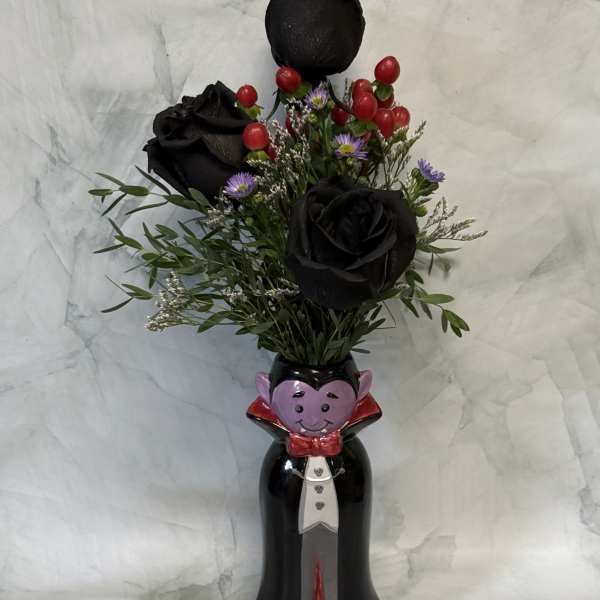 Black roses in a Halloween vampire vase with red berries