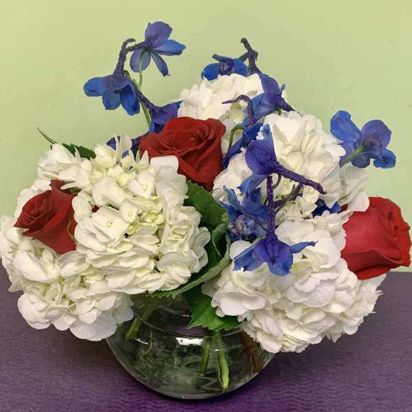Red roses and white hydrangeas with blue flowers in a glass vase