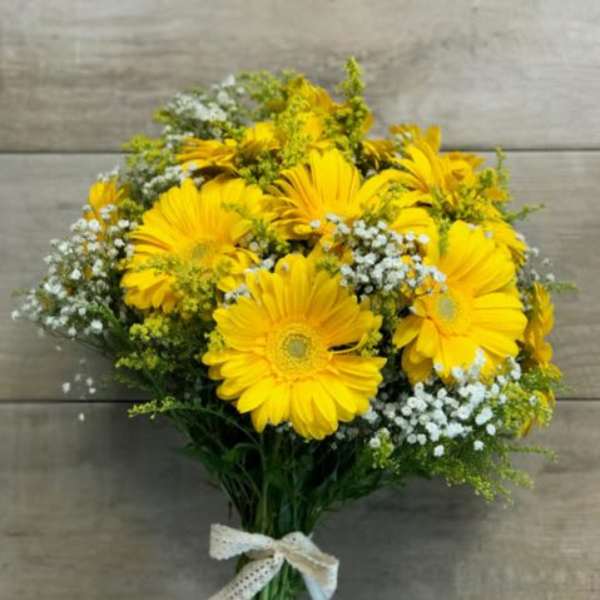 Bouquet of bright yellow gerbera daisies with white filler flowers tied with a lace ribbon