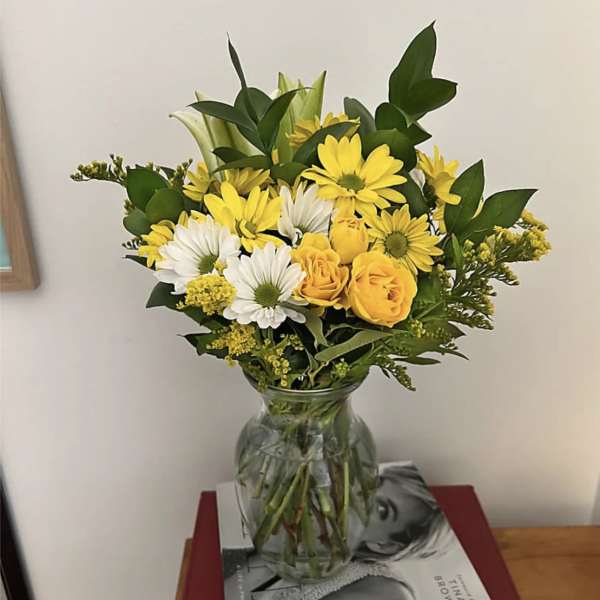 Yellow and white flowers arranged in a clear glass vase
