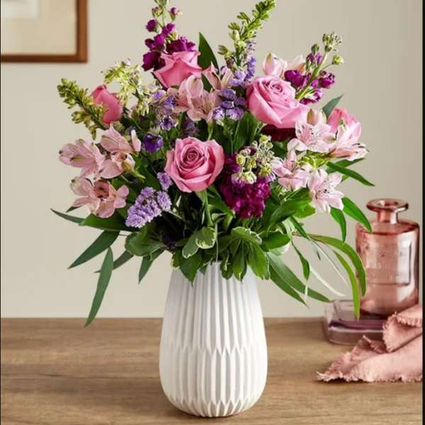 Pink roses and purple flowers in a white vase