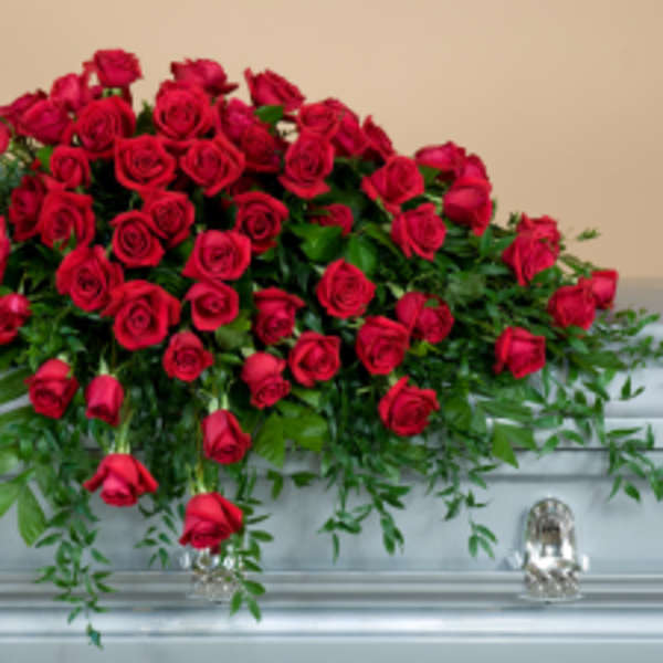 Red rose casket spray with trailing greenery on a silver casket