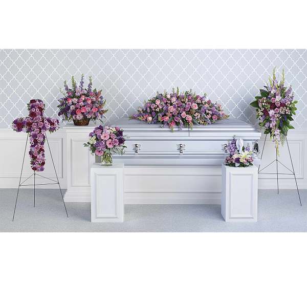 Funeral casket surrounded by pink and purple floral sprays