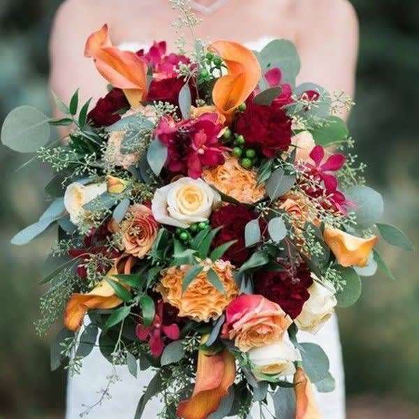 Bridal bouquet with orange calla lilies, red roses, and trailing eucalyptus