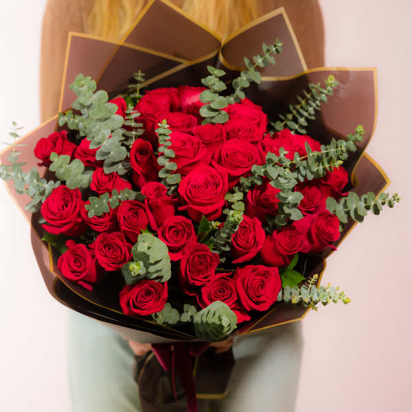 Bouquet of red roses with eucalyptus in dark wrapping