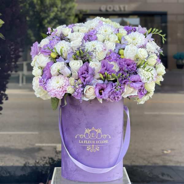 Lavender and white flower arrangement in a purple hatbox