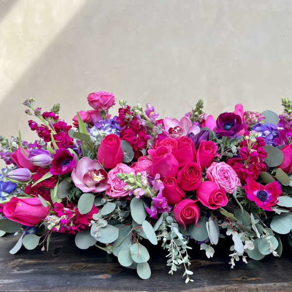 Low floral centerpiece with hot pink, purple, and blue blooms