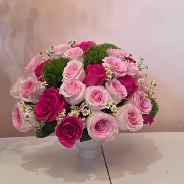 Pink and magenta roses arranged in a white vase