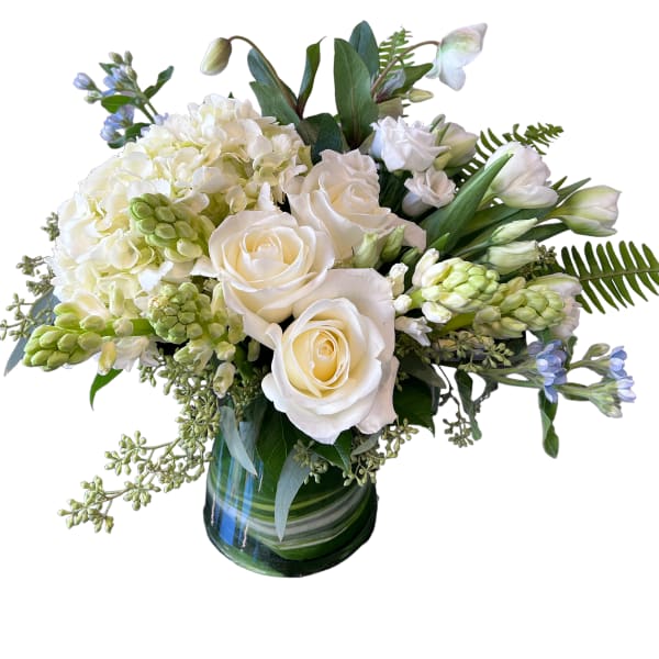 White roses and hydrangeas in a glass vase with blue accents