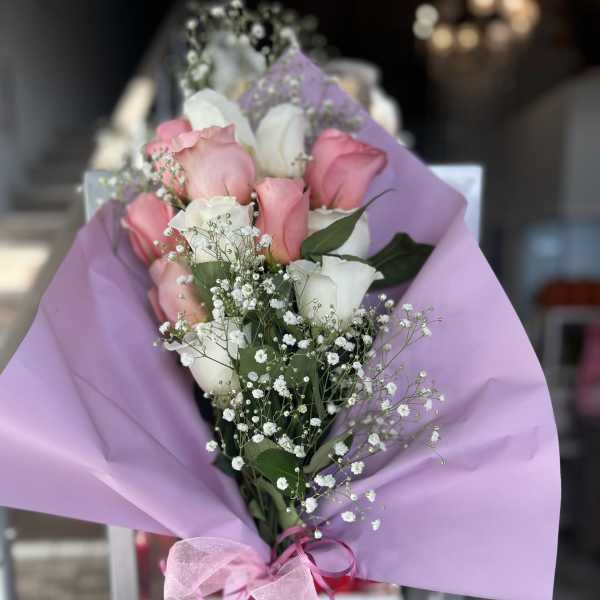Bouquet of pink and white roses wrapped in lavender paper