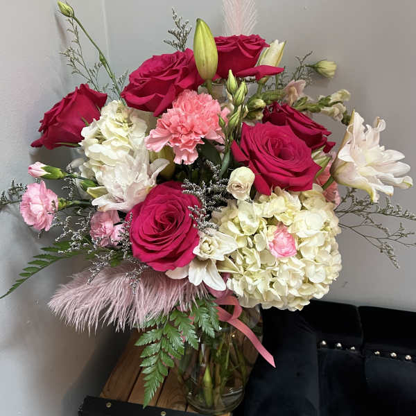 Bouquet of hot pink roses, white hydrangeas, and pink carnations in a glass vase