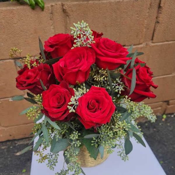 Arrangement of red roses in a gold vase on a white pedestal