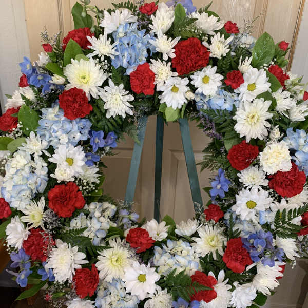 Large floral wreath with red, white, and blue flowers on a stand