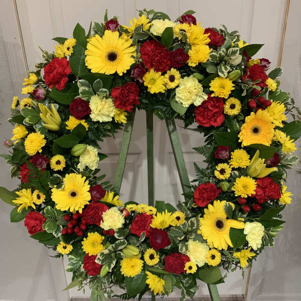 Large circular wreath of red and yellow flowers on a stand