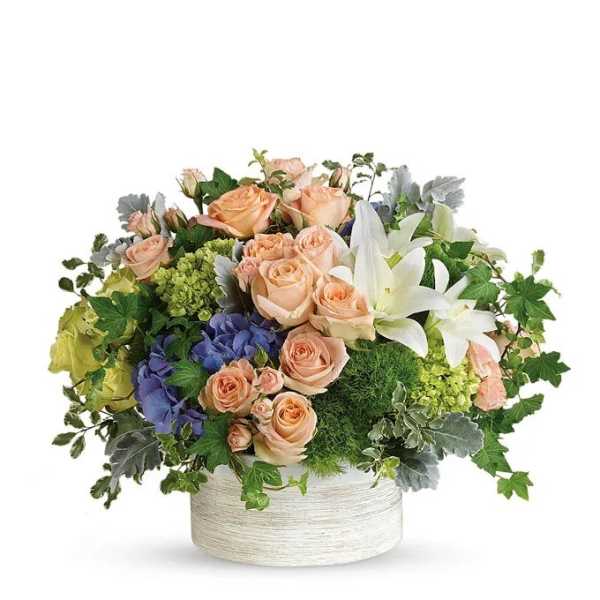 Peach roses and white lilies in a white round container