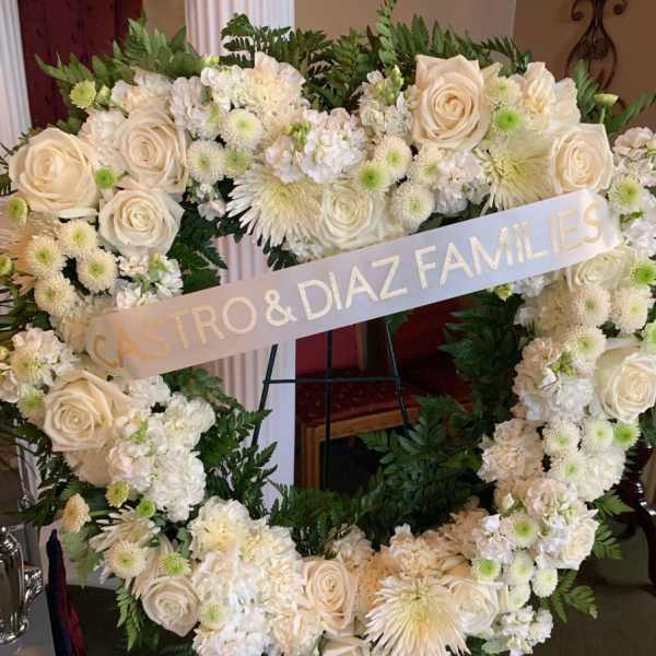 White floral heart wreath with a memorial ribbon on an easel