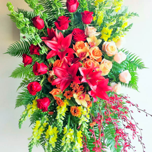 Large standing floral spray with red roses, lilies, and yellow blooms