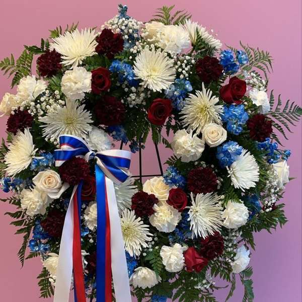 Large floral wreath with red, white, and blue flowers on a stand