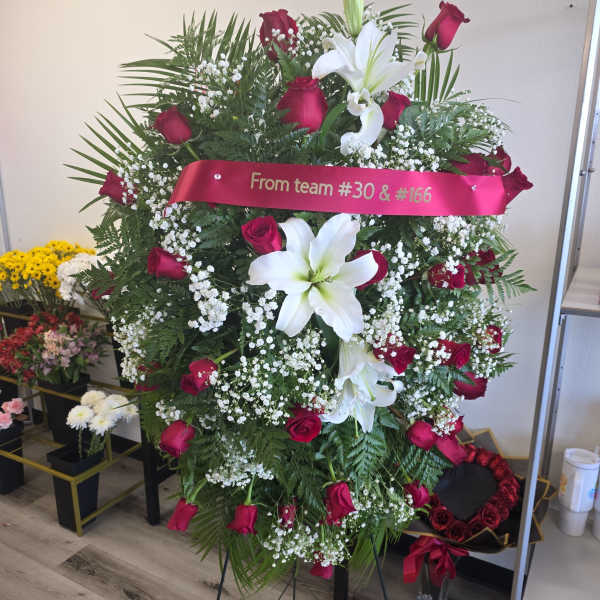 Standing floral spray with red roses and white lilies on an easel