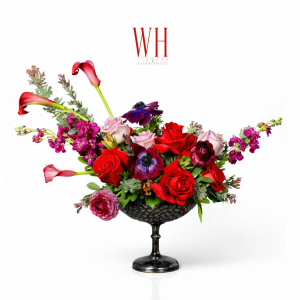 Mixed red and pink floral arrangement in a black pedestal bowl