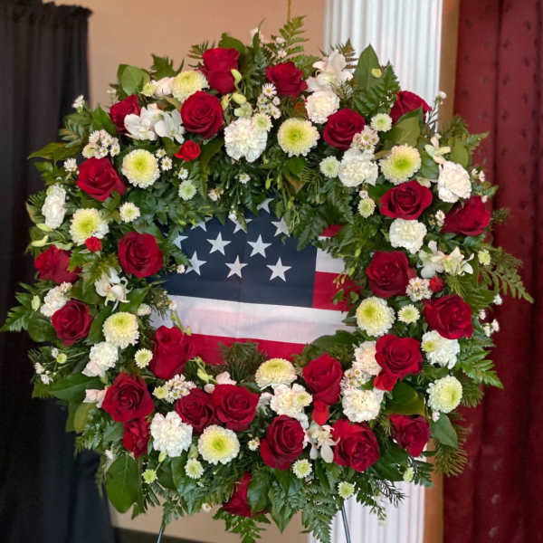 Red and white floral wreath around an American flag display