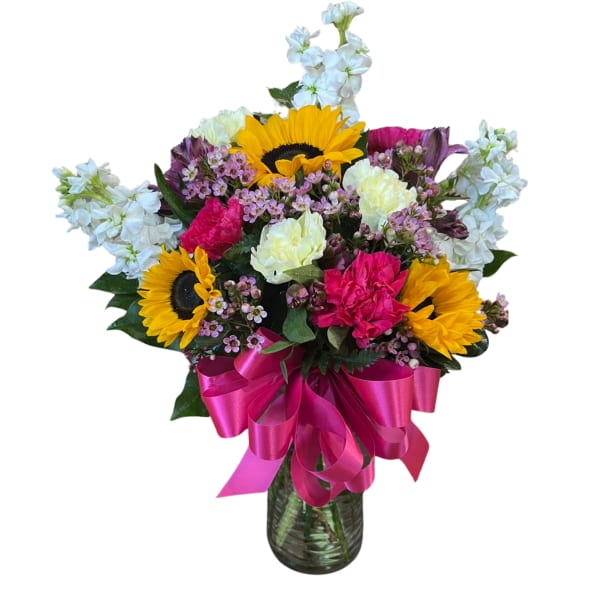 Bright mixed bouquet with sunflowers and pink and white flowers in a glass vase with a hot pink bow