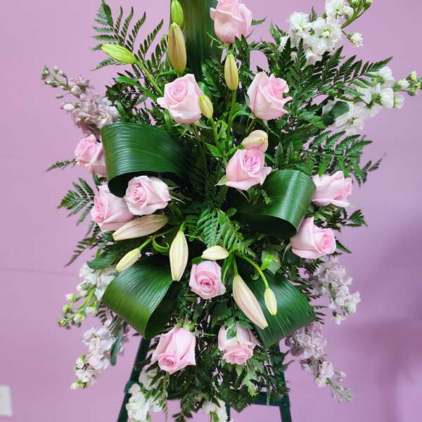 Standing floral spray with pink roses and white blooms on an easel