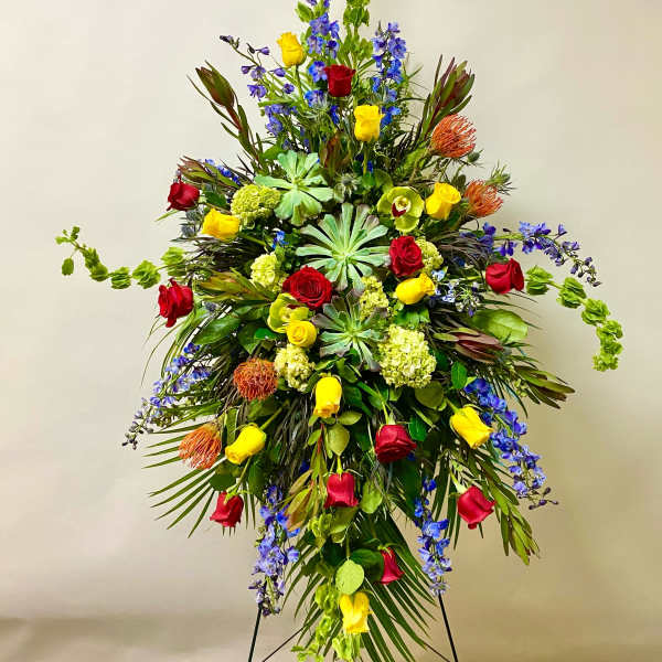 Large standing floral spray with red and yellow roses and blue flowers