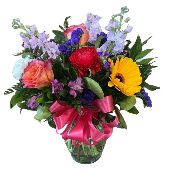 Bright mixed flower arrangement with yellow gerbera, roses, and red bloom in a clear vase with pink bow