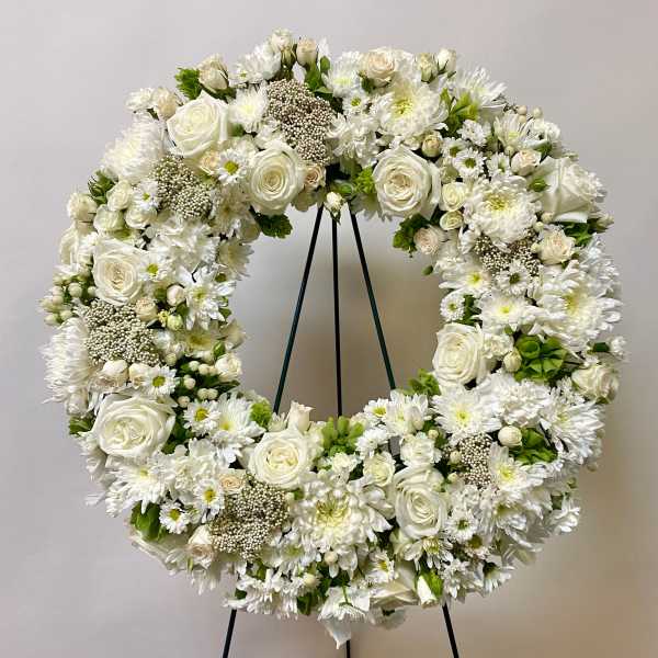 White floral wreath on a black stand